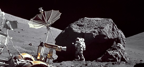 Apollo 17 astronautposes in front of large Moon rock